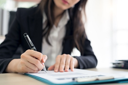 Close up of Businesswoman signing contract on table in office. Business Deal concept